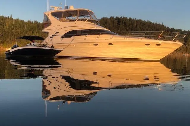 Hustler I Yacht Photos Pics 2000 Sea Ray 560 Sedan Bridge yacht reflecting on calm water at sunset.