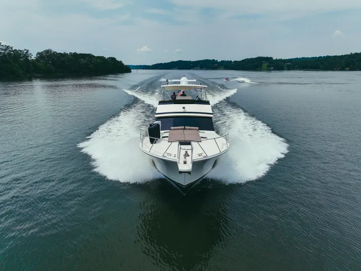 Lay A Wake Yacht Photos Pics 1990 Viking 53 Convertible yacht cruising on a serene lake, creating a dynamic water trail.