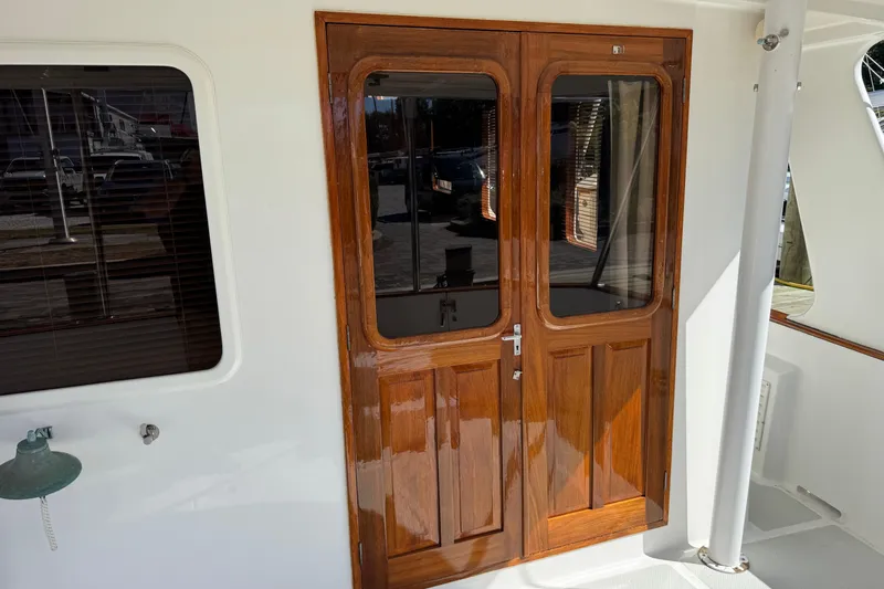 Marjorie Ann Yacht Photos Pics Polished wooden doors on a 2006 DeFever 52 Euro yacht, reflecting sunlight.