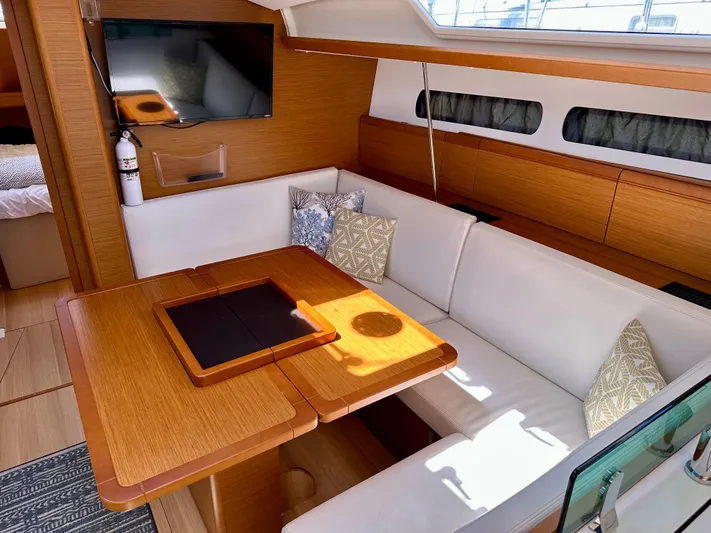 Celtic Rose Yacht Photos Pics 2018 Jeanneau Sun Odyssey 419 interior with cozy seating and wooden dining table.