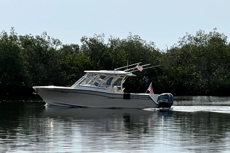 Liquid Carr-ma Yacht Photos Pics 2017 Grady-White Freedom 307 boat cruising on calm water near lush greenery.