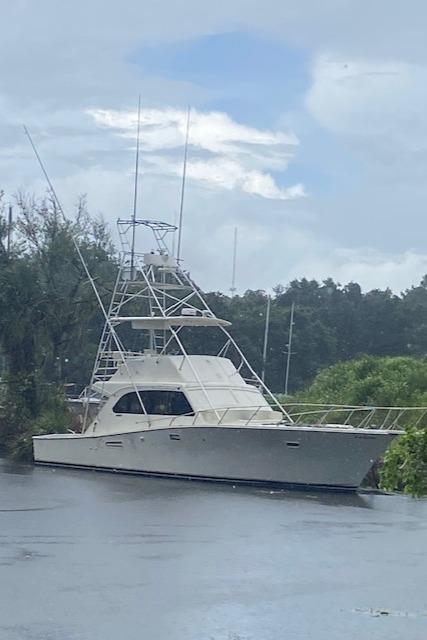 1984 Post 43 Sport Fisherman boat on calm water, surrounded by lush greenery.