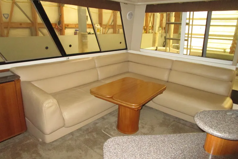 Yeah Yacht Photos Pics Luxurious interior of 1999 Bayliner 4788 Pilot House Motoryacht with beige seating and wooden table.
