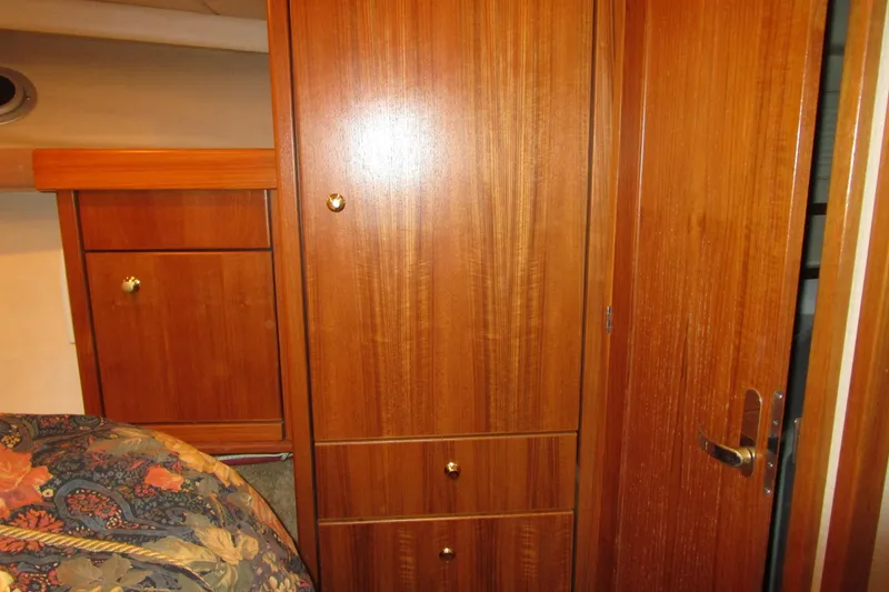 Yeah Yacht Photos Pics Wooden interior of 1999 Bayliner 4788 Pilot House Motoryacht, featuring cabinets and floral bedding.