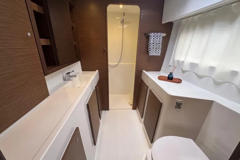 About Time Yacht Photos Pics Modern bathroom interior of 2021 Lagoon 42 yacht, featuring sleek design and wood accents.