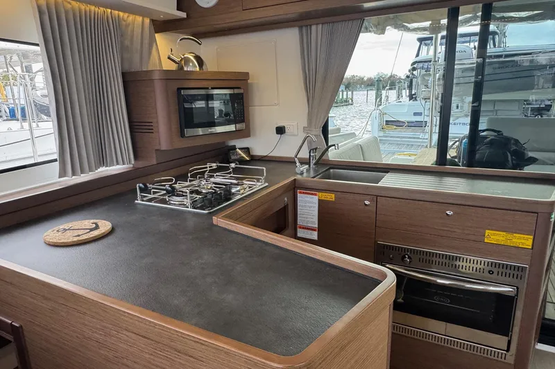 About Time Yacht Photos Pics Modern kitchen interior of 2021 Lagoon 42 catamaran with stove, sink, and microwave.