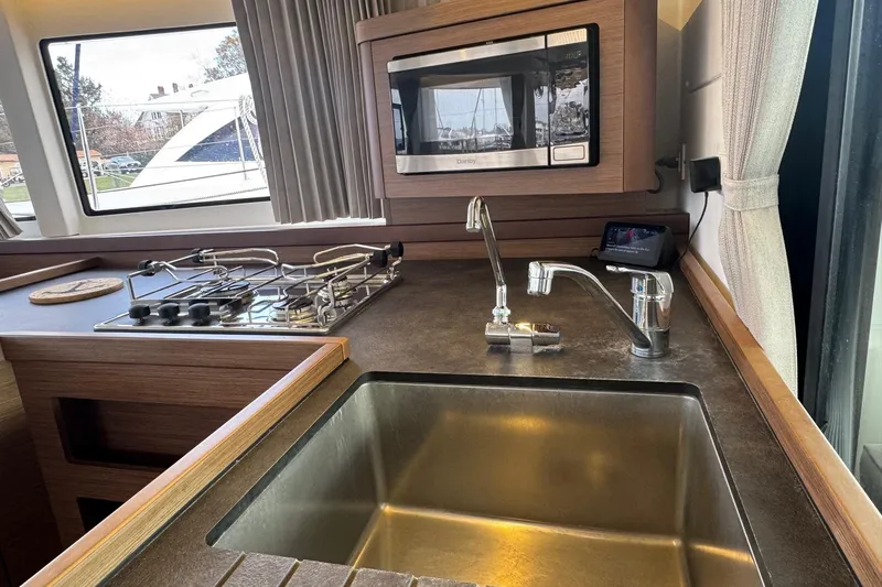 About Time Yacht Photos Pics Modern kitchen interior of 2021 Lagoon 42 yacht with stove, sink, and microwave.