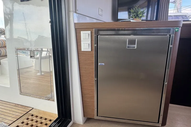 About Time Yacht Photos Pics Stainless steel fridge on 2021 Lagoon 42 yacht interior, with wooden accents and outdoor view.