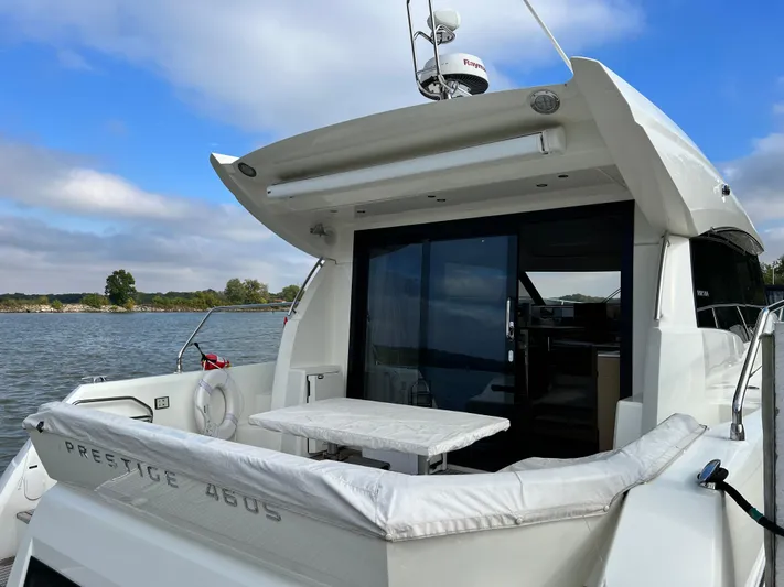  Yacht Photos Pics 2018 Prestige 460 yacht with outdoor seating, docked by a scenic waterway.