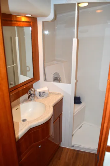 Quite Nice Yacht Photos Pics 2004 Bertram 570 Convertible yacht bathroom with shower, sink, and wooden cabinetry.