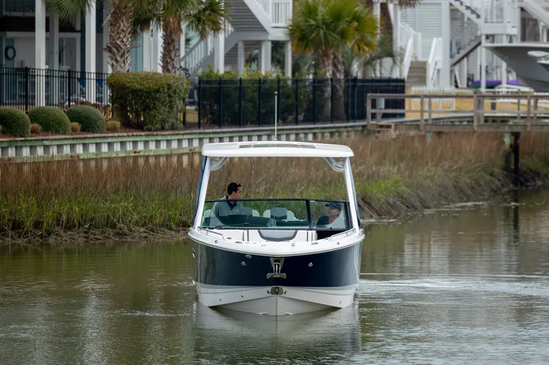  Yacht Photos Pics 2023 Chaparral 280 OSX boat cruising on a calm waterway near waterfront homes.