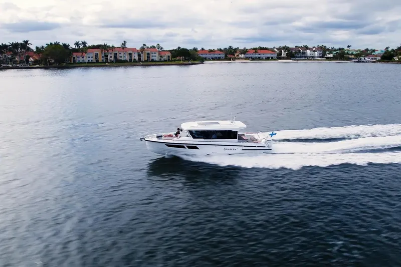  Yacht Photos Pics 2025 Quarken 35 Cabin boat cruising on a calm lake near residential area.