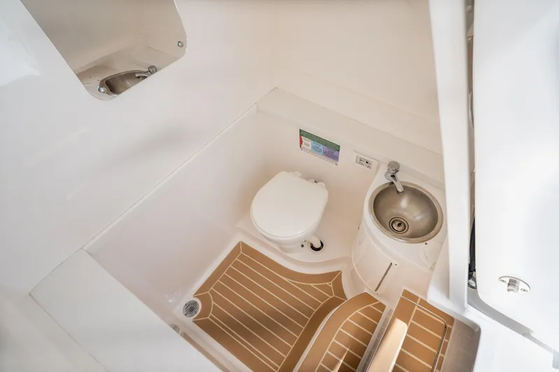 Freaky Fast Yacht Photos Pics 2018 Intrepid 375 Open boat bathroom with toilet, sink, and wooden floor mat.