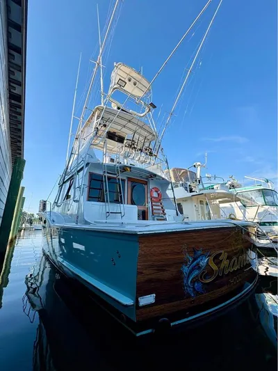 Shameless Yacht Photos Pics 1983 Hatteras 46 Convertible yacht docked, featuring a sleek design and fishing equipment.