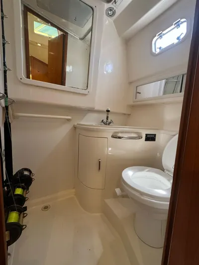 No Problem Yacht Photos Pics 1998 Cabo 35 Express boat bathroom with toilet, sink, and fishing rods.