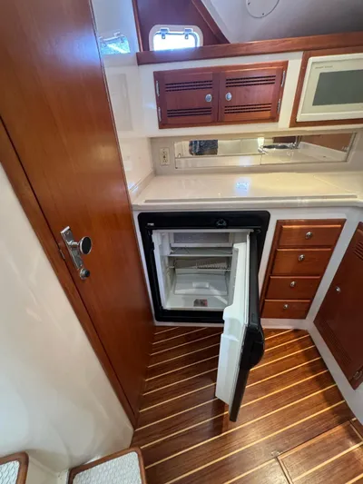 No Problem Yacht Photos Pics 1998 Cabo 35 Express yacht interior with open fridge, wooden cabinets, and striped flooring.