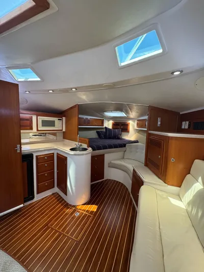 No Problem Yacht Photos Pics 1998 Cabo 35 Express interior with wood flooring, kitchenette, and seating area.