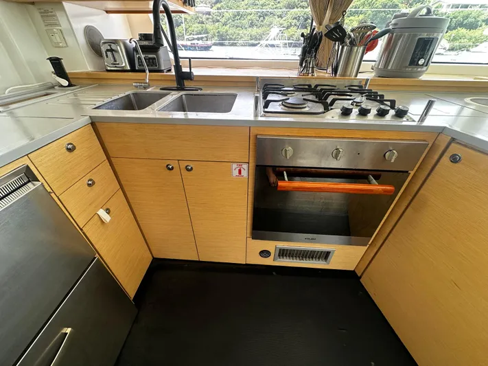  Yacht Photos Pics Modern kitchen in a 2017 Lagoon 52 F yacht with stove, sink, and wooden cabinetry.