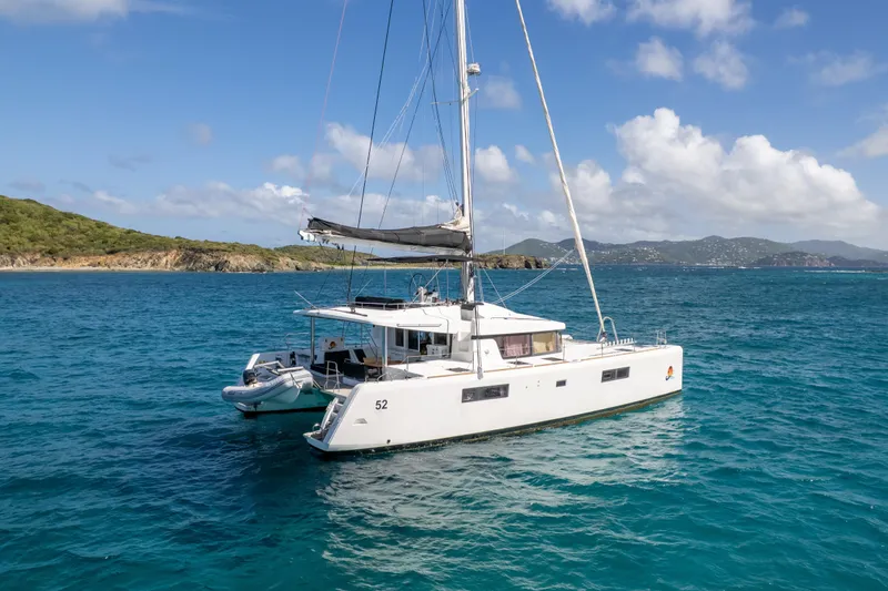  Yacht Photos Pics 2017 Lagoon 52 F catamaran sailing in clear blue waters near a scenic coastline.