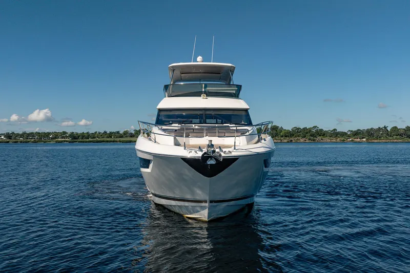 No Rush Yacht Photos Pics Front view of a 2018 Prestige 630 yacht on calm water under a clear blue sky.
