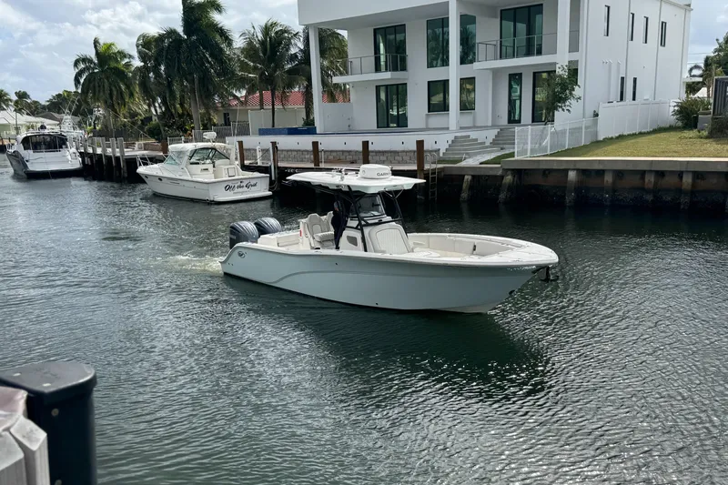  Yacht Photos Pics 2022 Sea Fox 288 Commander boat cruising in a canal near modern waterfront homes.