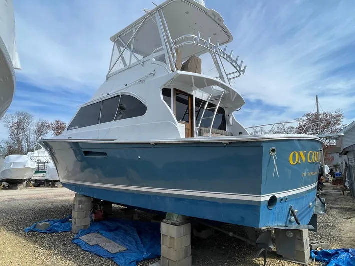 On Course Yacht Photos Pics 1986 Egg Harbor 41 Convertible boat on blocks, blue hull, white superstructure, outdoor setting.