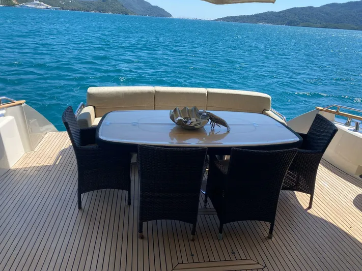 Tyche Yacht Photos Pics Luxury dining area on 2019 Monte Carlo Yachts MCY 76, overlooking serene blue waters.