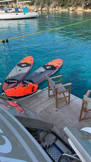 Tyche Yacht Photos Pics Monte Carlo Yachts MCY 76, 2019 model, with paddleboards on a serene blue water backdrop.