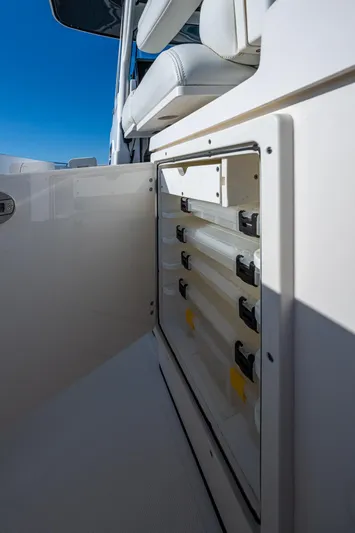 @c Yacht Photos Pics 2022 Pursuit S 268 Sport boat storage compartment with tackle boxes, under clear blue sky.