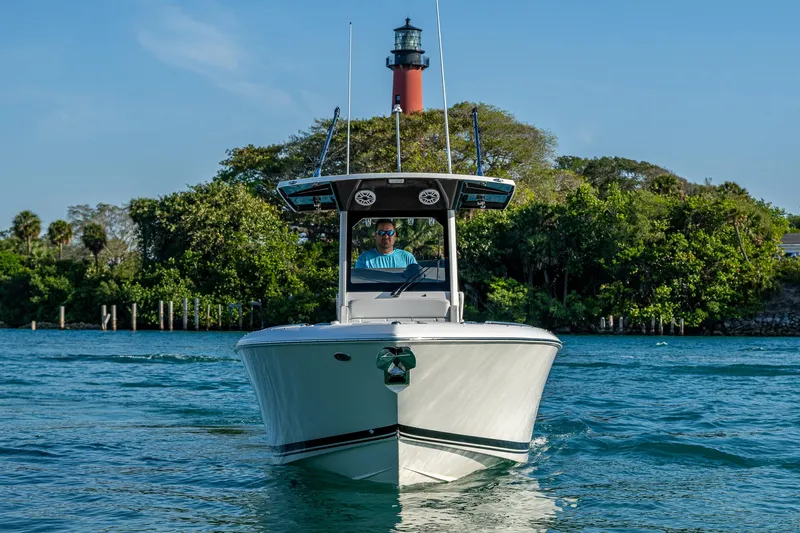 @c Yacht Photos Pics 2022 Pursuit S 268 Sport boat cruising near a lighthouse with lush greenery.
