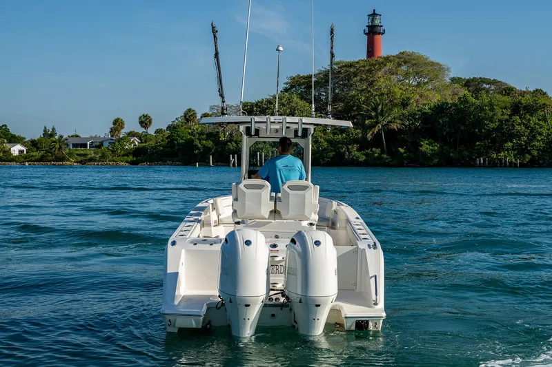 @c Yacht Photos Pics 2022 Pursuit S 268 Sport boat on water near lush island and lighthouse.