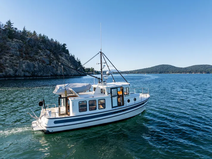 Naukati II Yacht Photos Pics 2000 Nordic Tug 32 cruising on scenic blue waters near rocky shoreline.