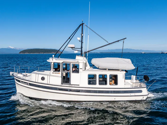 Naukati II Yacht Photos Pics 2000 Nordic Tug 32 cruising on blue ocean with clear sky background.