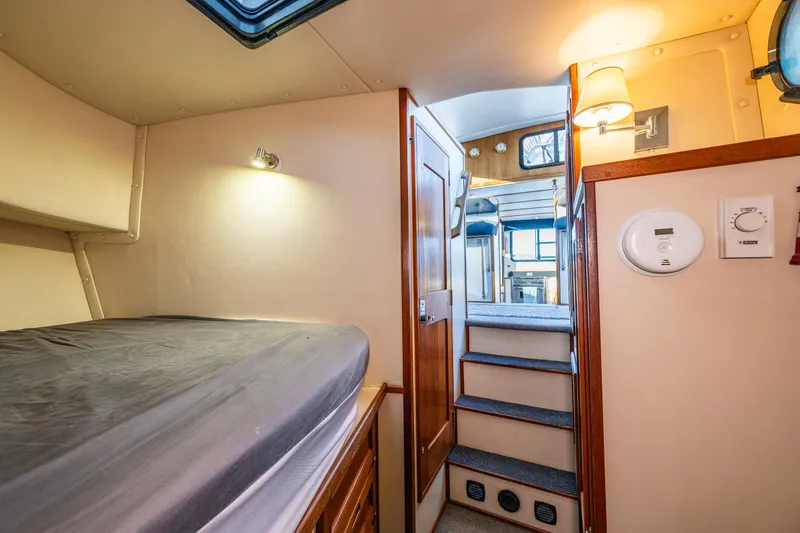 Naukati II Yacht Photos Pics Cozy cabin interior of 2000 Nordic Tug 32 with bed, stairs, and wooden accents.