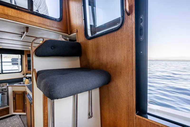 Naukati II Yacht Photos Pics Interior of 2000 Nordic Tug 32, featuring a cushioned seat and wooden cabinetry.