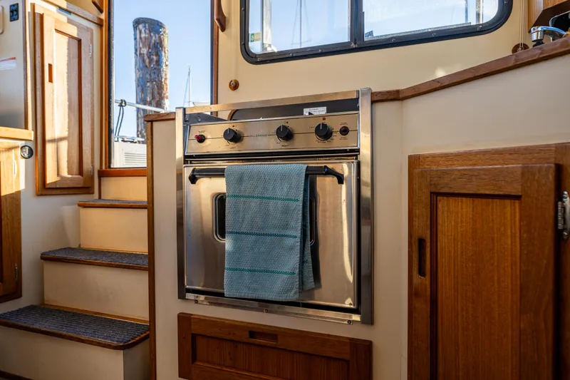 Naukati II Yacht Photos Pics Interior of a 2000 Nordic Tug 32 featuring a stainless steel oven and wooden cabinetry.