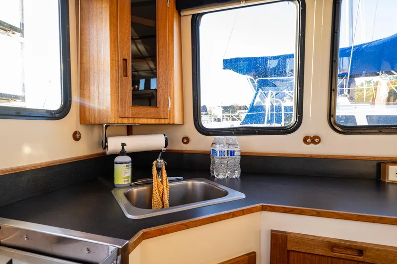Naukati II Yacht Photos Pics Interior of 2000 Nordic Tug 32, featuring a compact kitchen with sink and wooden cabinetry.