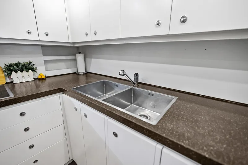 Diamond Yacht Photos Pics Modern kitchen sink area on 2013 AB 116 Motoryacht with sleek countertops and white cabinetry.