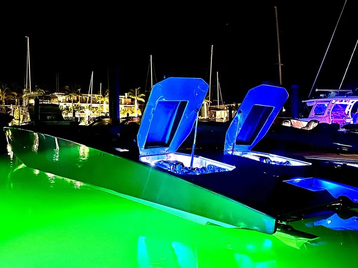  Yacht Photos Pics Illuminated Skater 46 boat with open hatches, glowing green water at night.