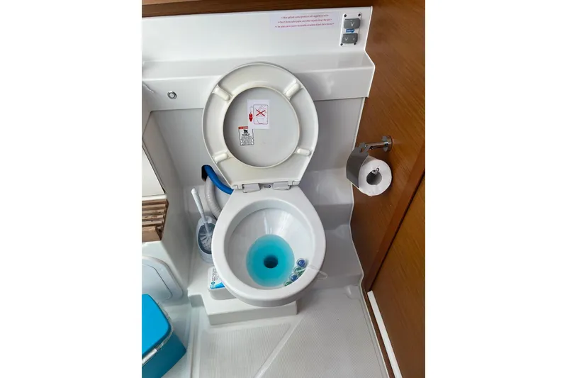 Cicerenella Yacht Photos Pics Toilet in 2019 Jeanneau Sun Odyssey 440 yacht bathroom, featuring modern fixtures and blue cleaning solution.