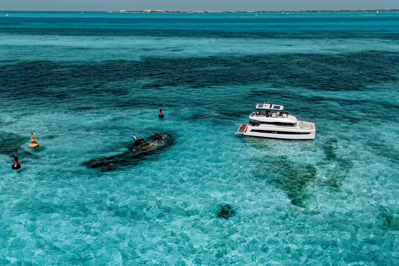 Libert'e Yacht Photos Pics 2020 Fountaine Pajot MY6 yacht on clear turquoise waters near a shipwreck.