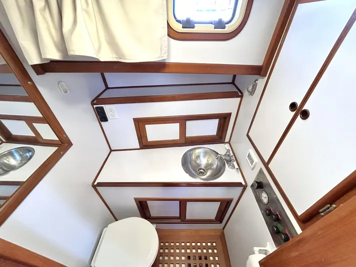  Yacht Photos Pics 1987 Marine Trader 44 Sunbridge Trawler bathroom with wood accents, sink, and porthole window.