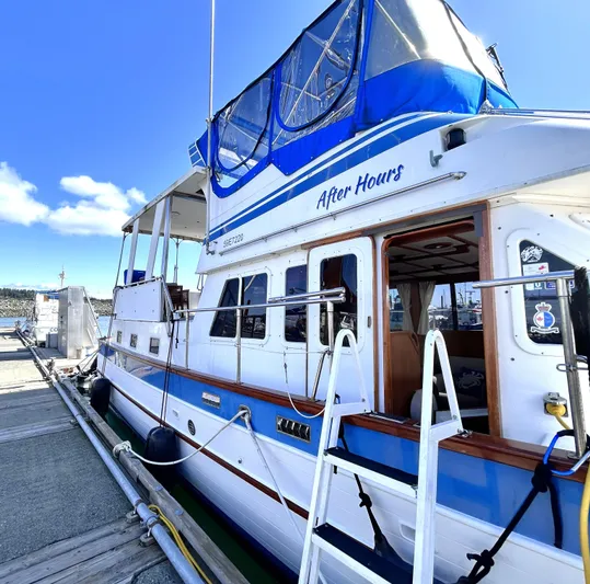  Yacht Photos Pics 1987 Marine Trader 44 Sunbridge Trawler docked, featuring blue accents and upper deck canopy.