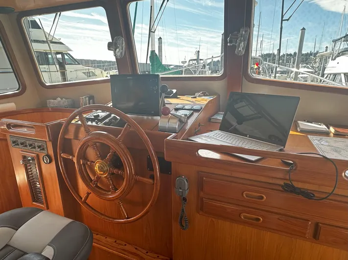 Brut Yacht Photos Pics 1999 Krogen Trawler helm with wooden wheel, navigation equipment, and marina view.