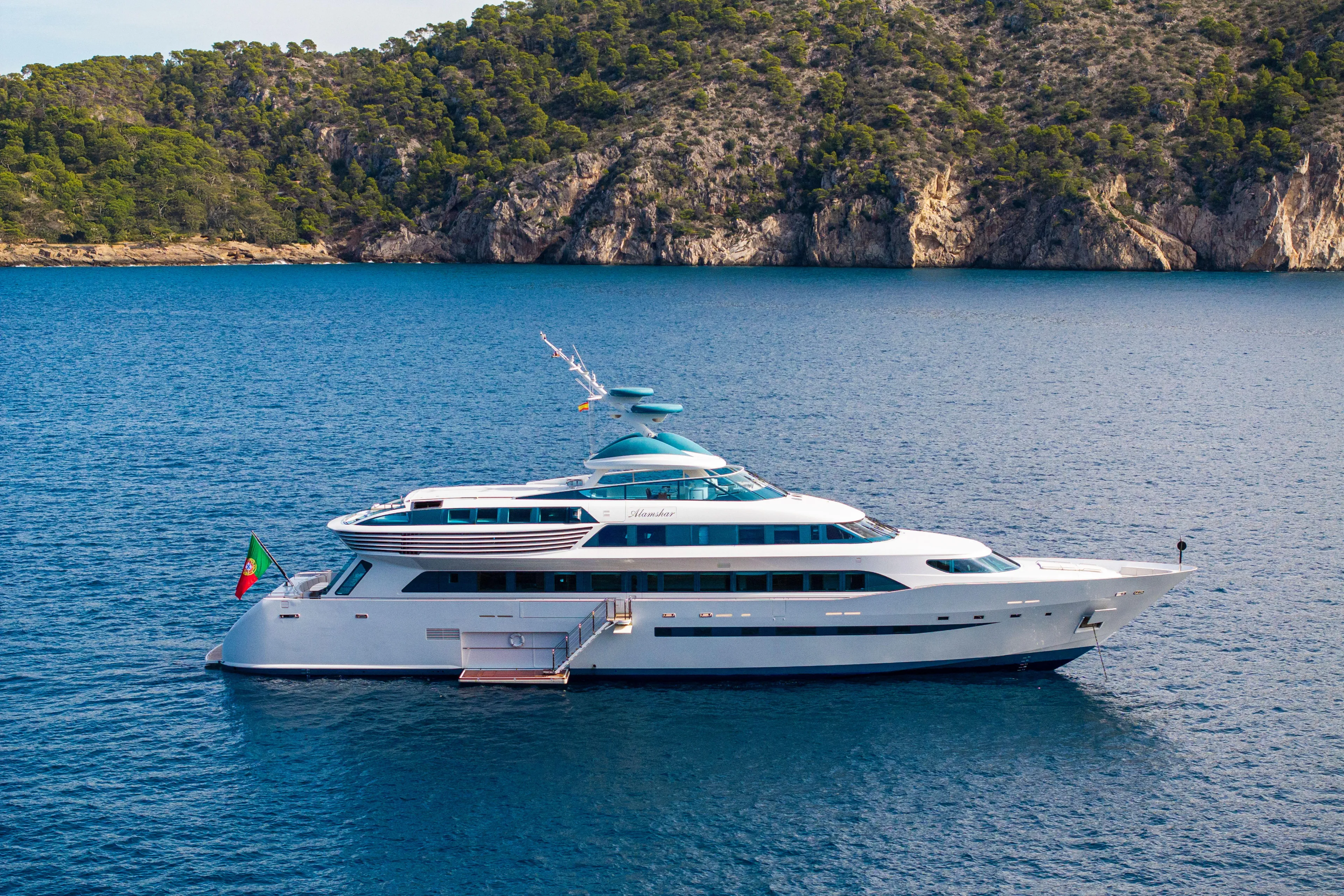 Luxurious Devonport yacht on serene blue waters, 2014 model, with scenic rocky coastline backdrop.