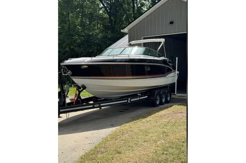  Yacht Photos Pics 2014 Formula 310 Bowrider on trailer outside a garage, surrounded by trees.