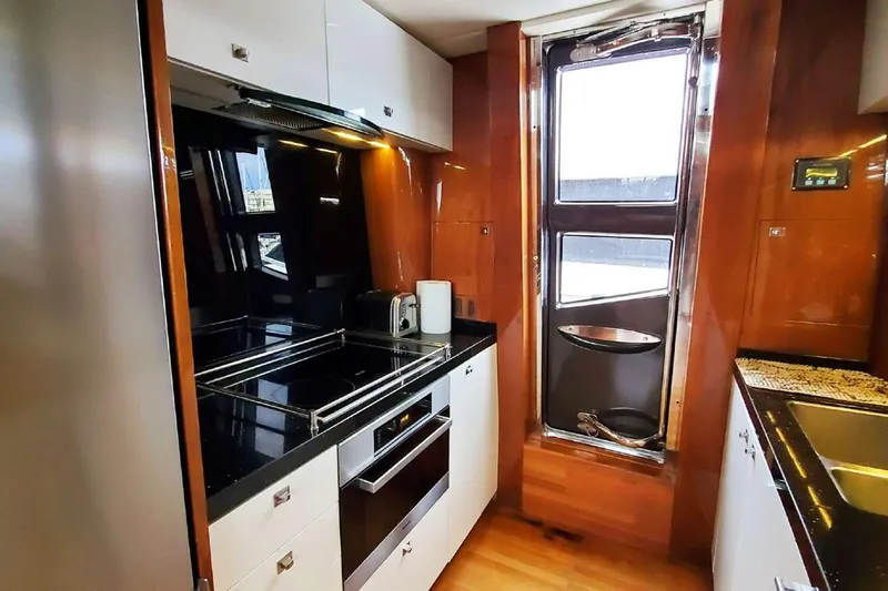  Yacht Photos Pics Luxurious kitchen interior on a 2014 Princess 82 yacht, featuring modern appliances and wood finishes.