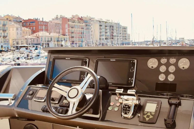  Yacht Photos Pics Helm of 2014 Princess 82 yacht with navigation equipment, overlooking marina and colorful buildings.