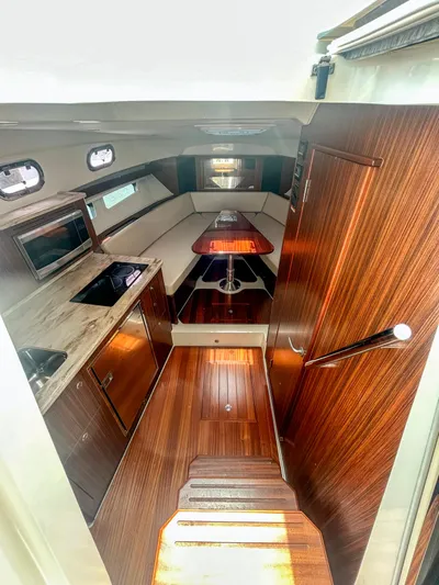  Yacht Photos Pics 2018 Pursuit OS 355 Offshore cabin interior with wood finish and kitchenette.