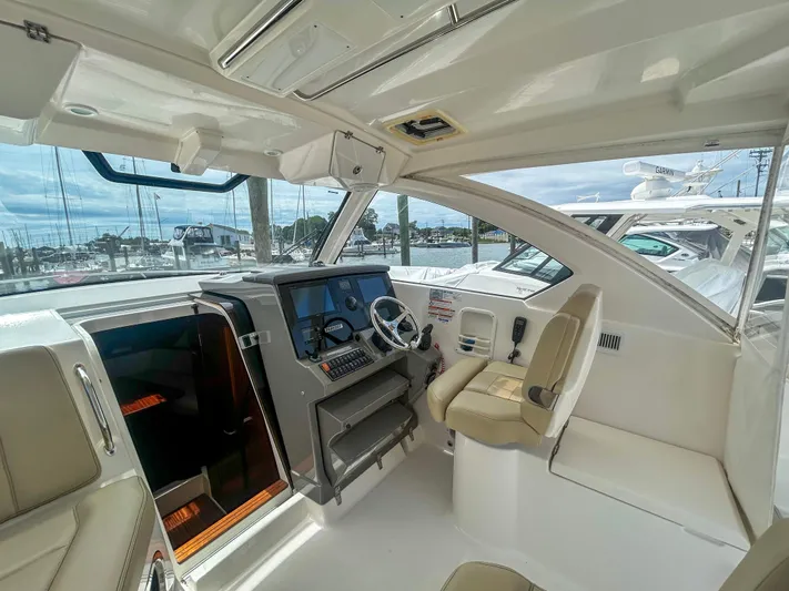  Yacht Photos Pics 2018 Pursuit OS 355 Offshore boat interior with helm, beige seating, and marina view.